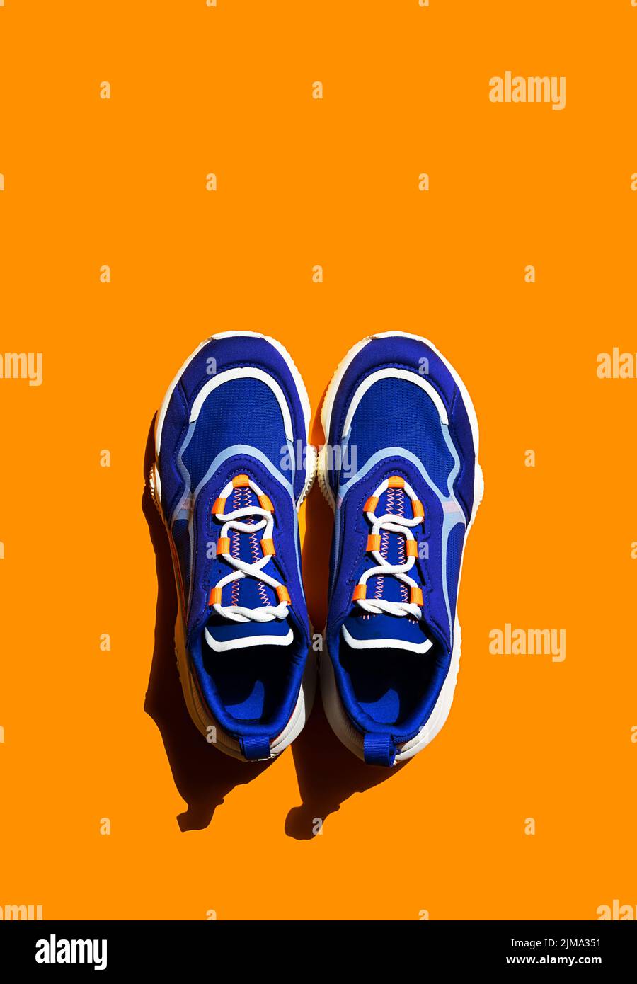 Blue sneakers on orange background. Trendy sport shoe, street casual footwear. Stock Photo
