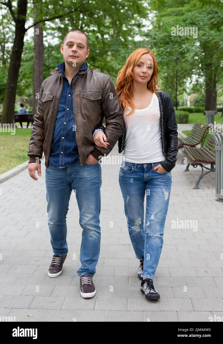 Young woman and man walking in city park holding hands Stock Photo - Alamy