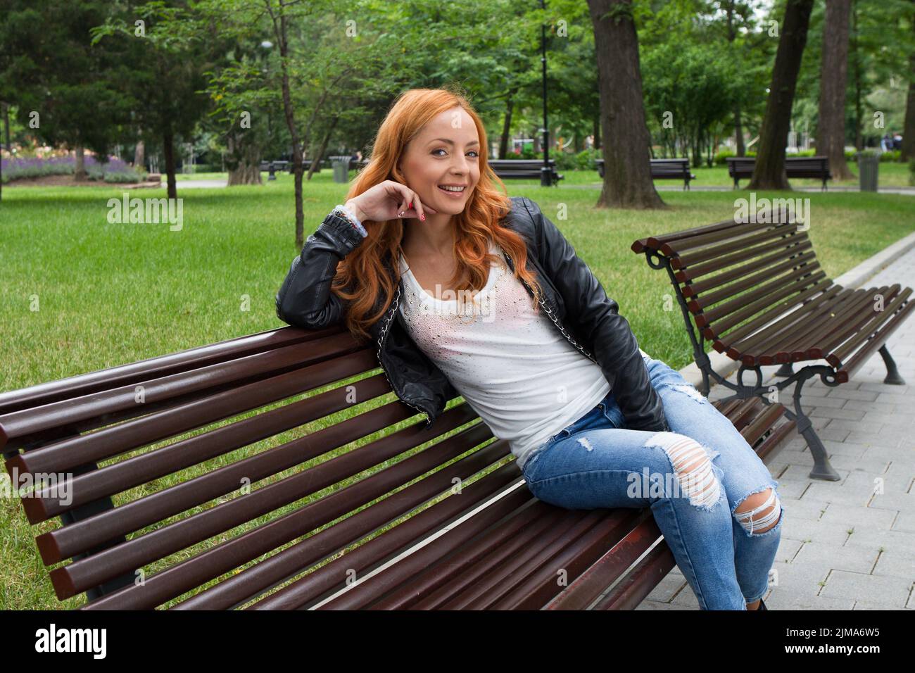 Beautiful blond woman sitting on bench in park outdoors Stock Photo - Alamy