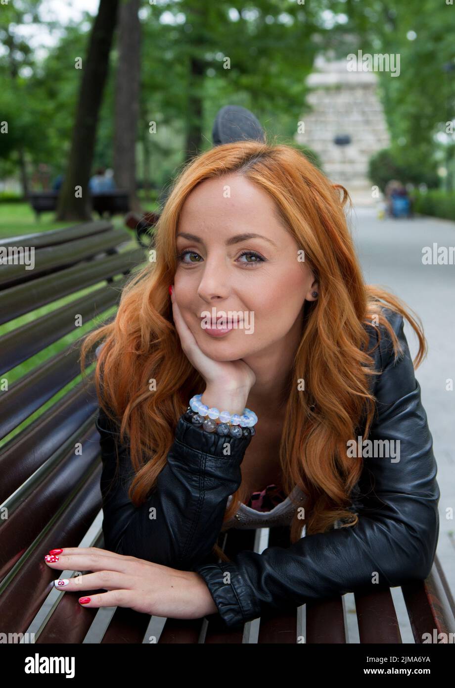 Beautiful blond woman sitting on bench in park outdoors Stock Photo - Alamy