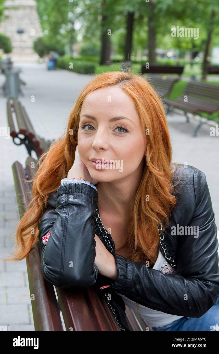 Beautiful blond woman sitting on bench in park outdoors Stock Photo - Alamy