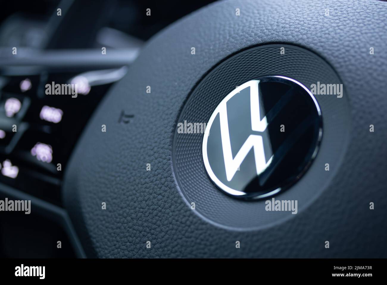 A chrome Volkswagen, VW badge on the centre of a new vehicle steering wheel. Stock Photo