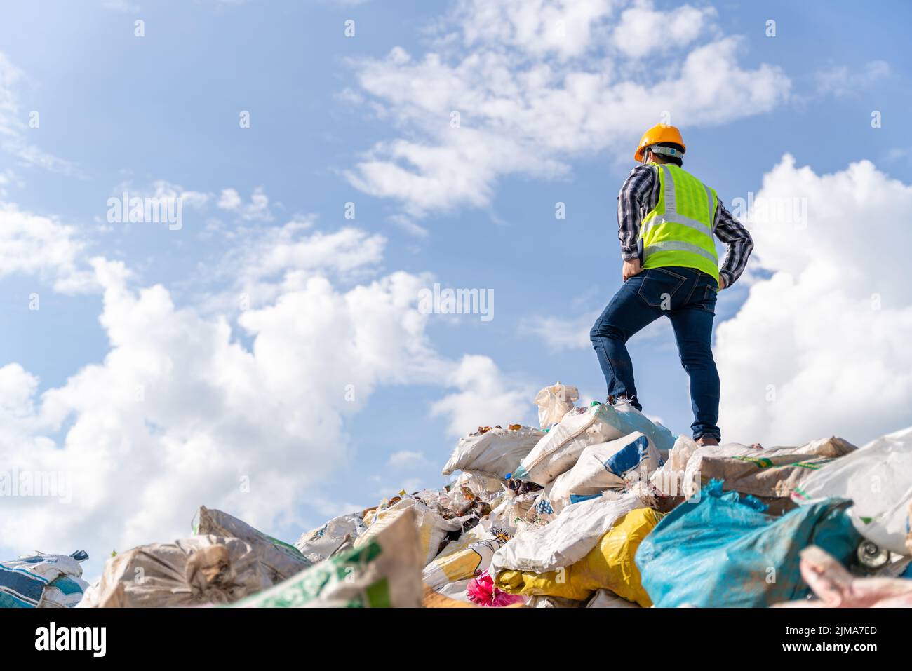 A manager stands holding a tablet on top of the recycling bin at