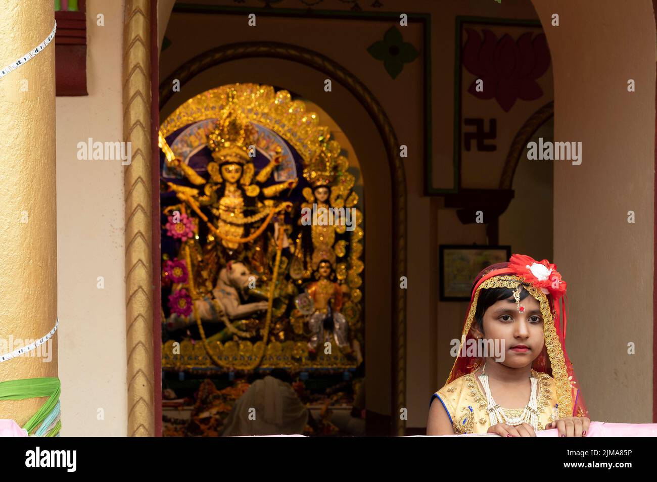 Howrah,India -October 26th,2020 : Bengali girl child in festive dress, smiling and posing with Goddess Durga in background, inside old age decorated h Stock Photo