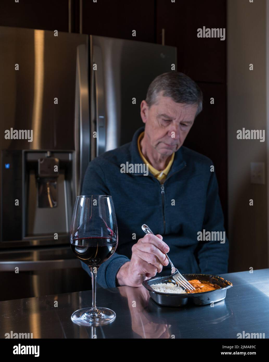 Lonely senior man eating ready meal at table Stock Photo