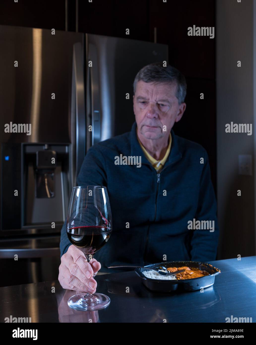 Lonely senior man eating ready meal at table Stock Photo