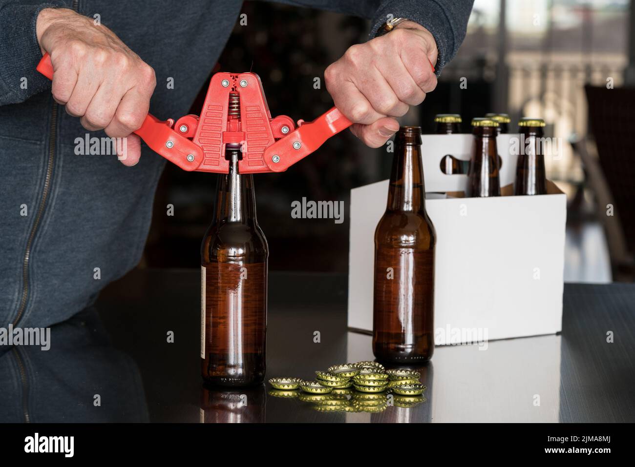 Man using capper to put metal caps on beer bottle Stock Photo