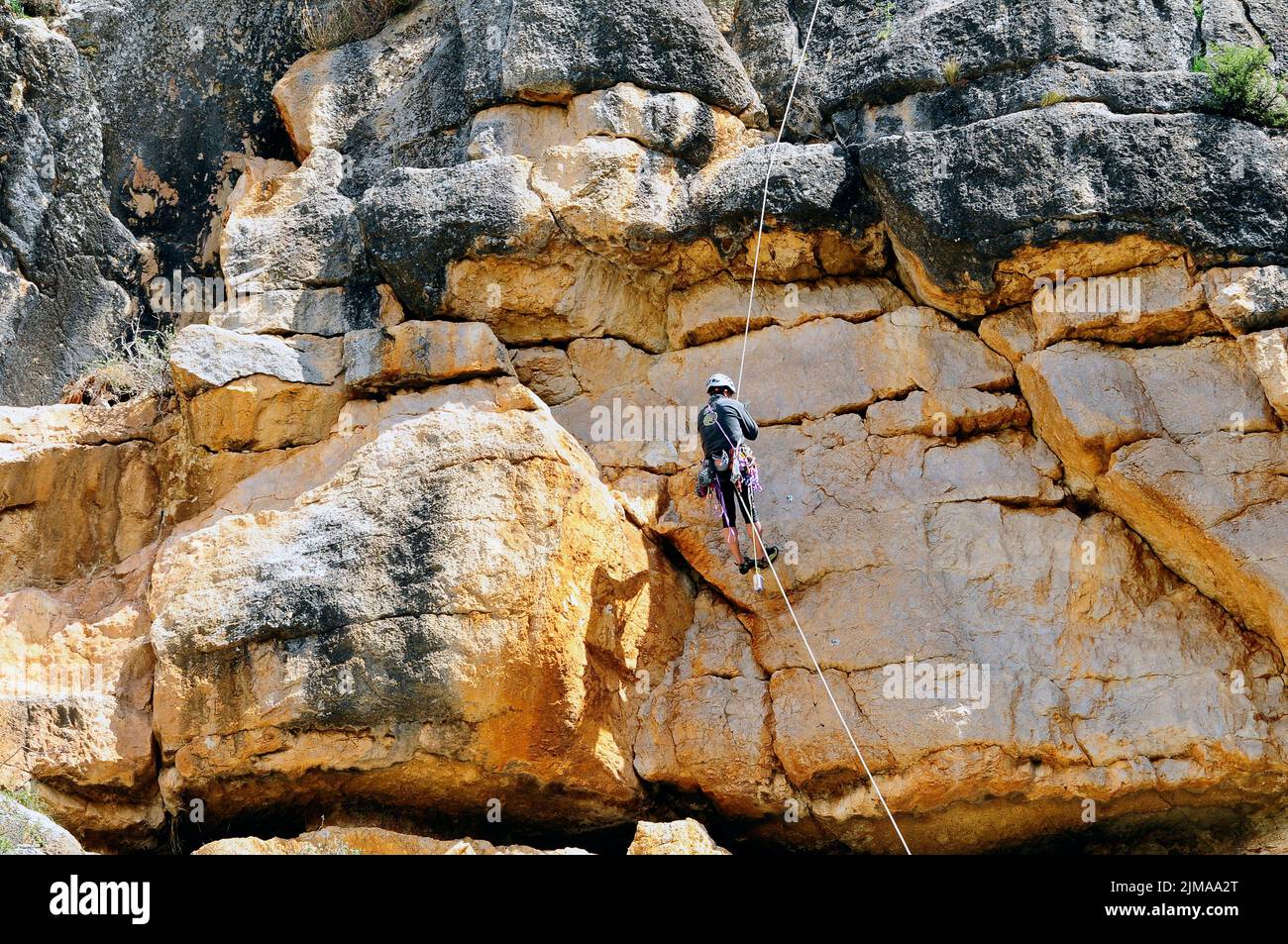 A rock climber with a safety rope, climbing on a flat rock with