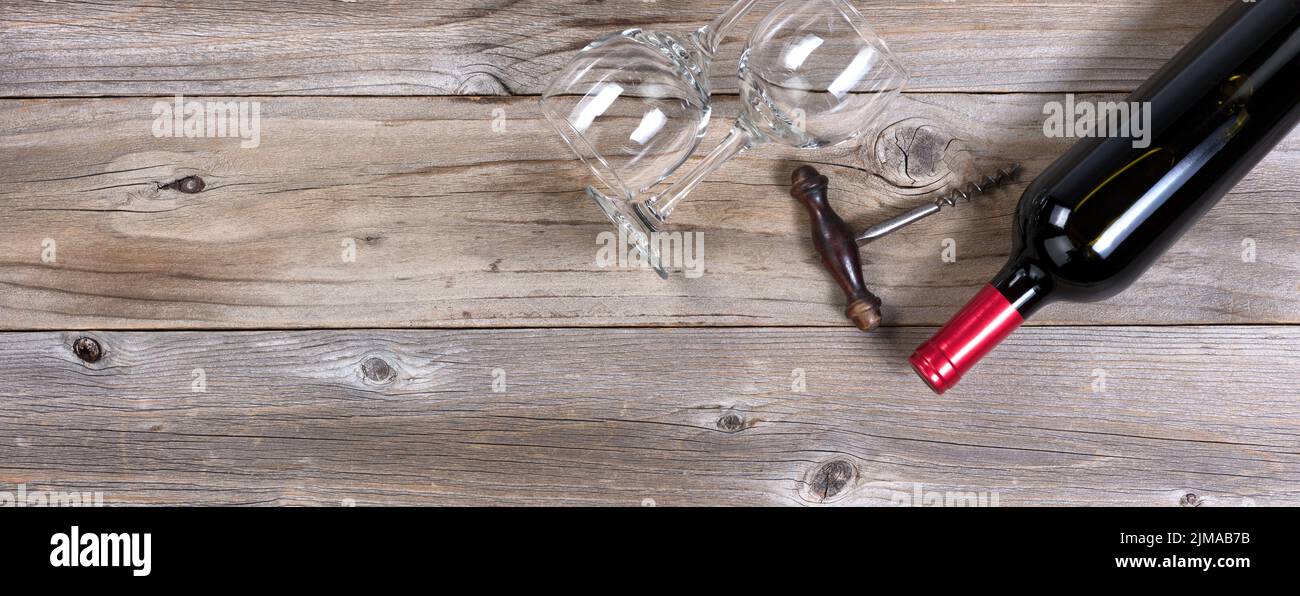 Unopen bottle of red wine and clean drinking glasses on rustic wooden boards Stock Photo
