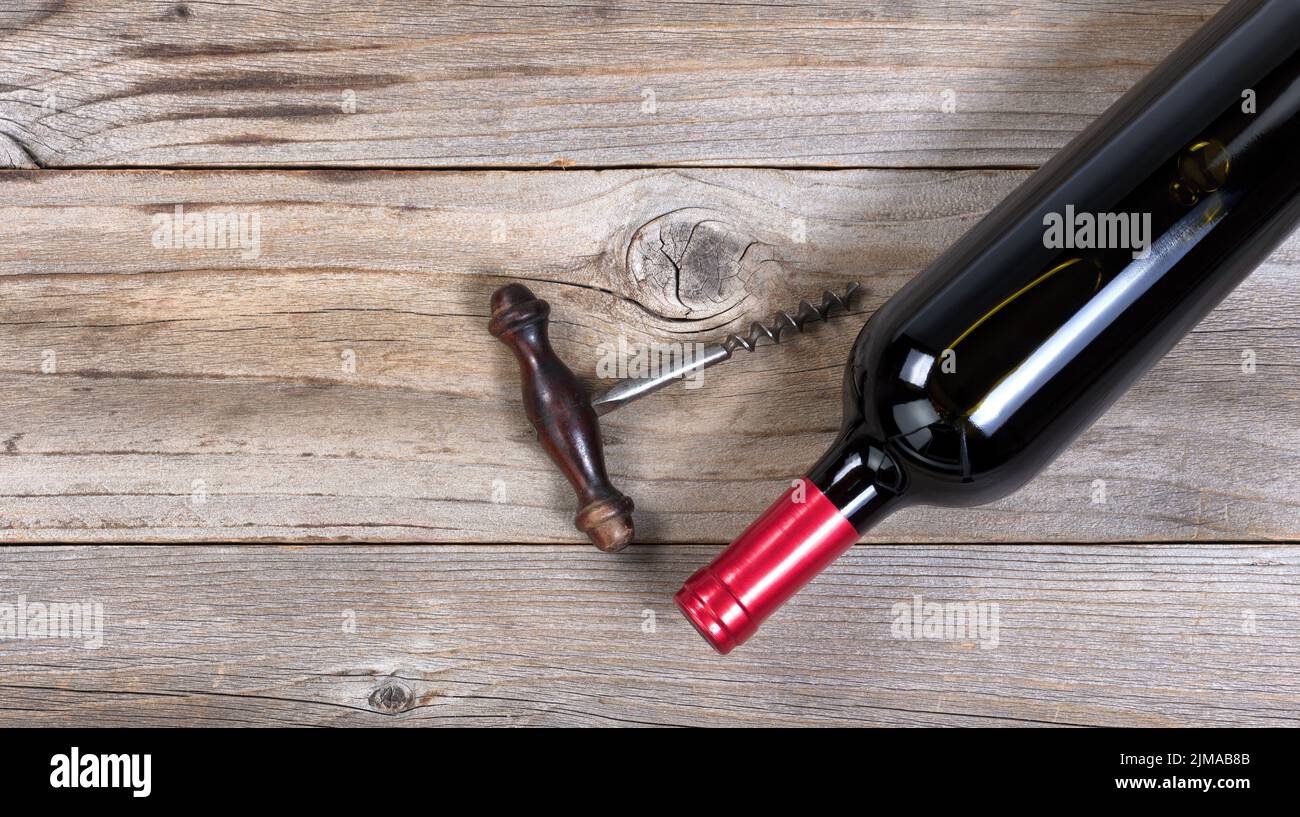 Unopen bottle of red wine with vintage corkscrew on rustic wooden boards Stock Photo
