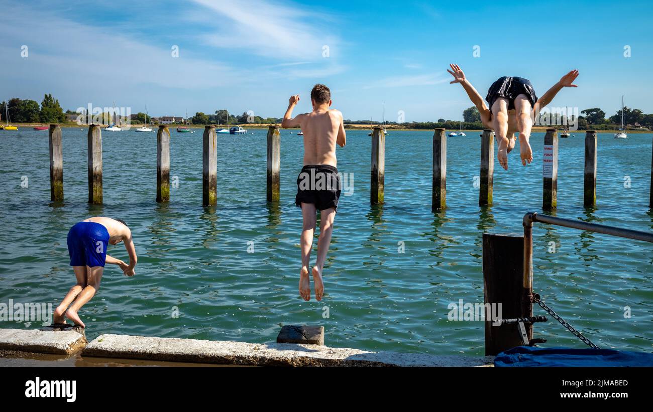 Three teenage boys ready themselves to dive into the sea at high tide