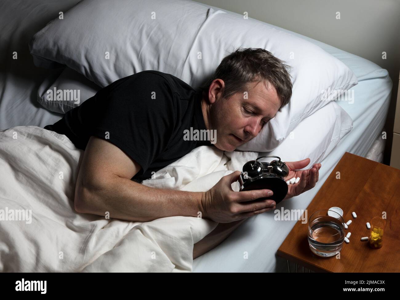 Mature man having difficulty falling asleep at night thus taking medicine Stock Photo