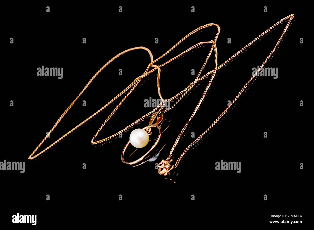 Golden chain with pendant on black mirrored surface Stock Photo