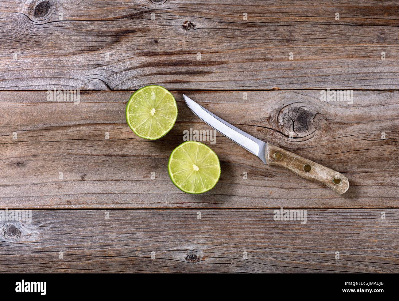 Sliced lime and paring knife on rustic wood in flat lay format Stock Photo