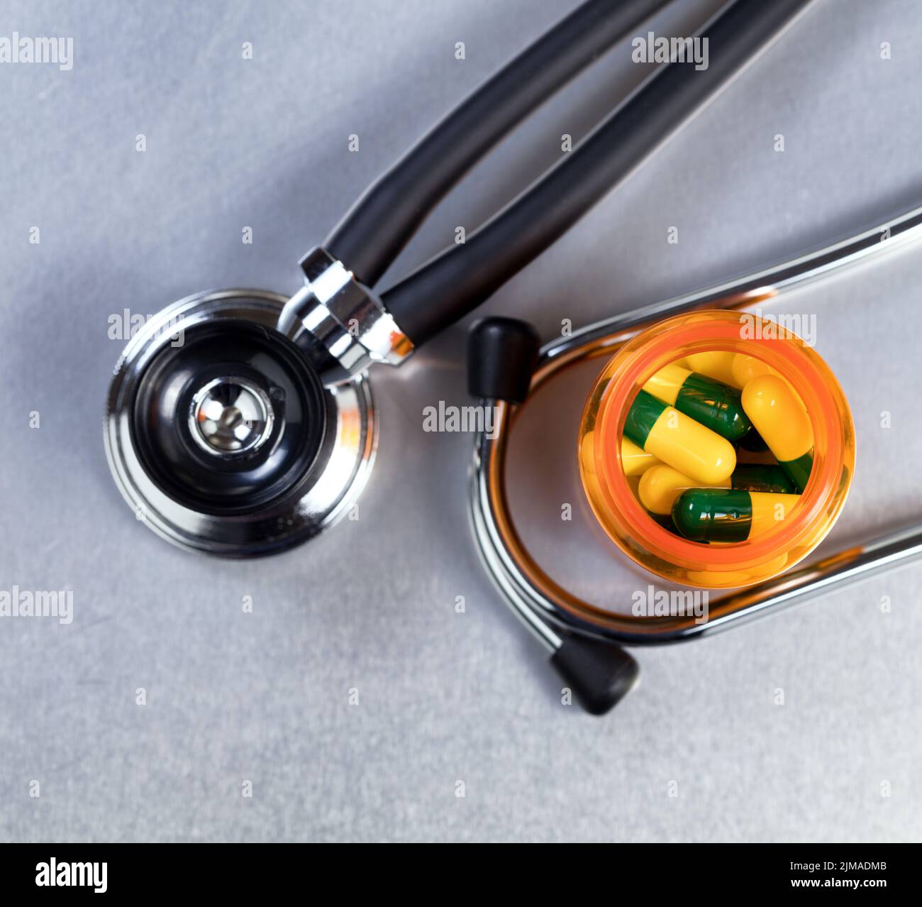 Medicine bottle filled with capsules on stainless steel table with stethoscope Stock Photo
