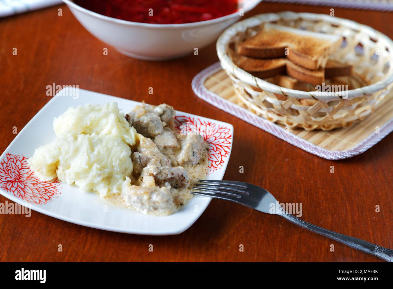 Plate of potatoes with meat and croutons on the kitchen table Stock Photo