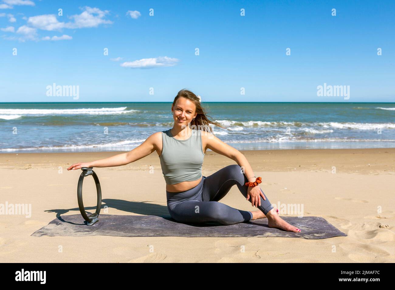 beauty fitness instructor with a pilates ring near the sea, female fitness yoga routine concept Stock Photo
