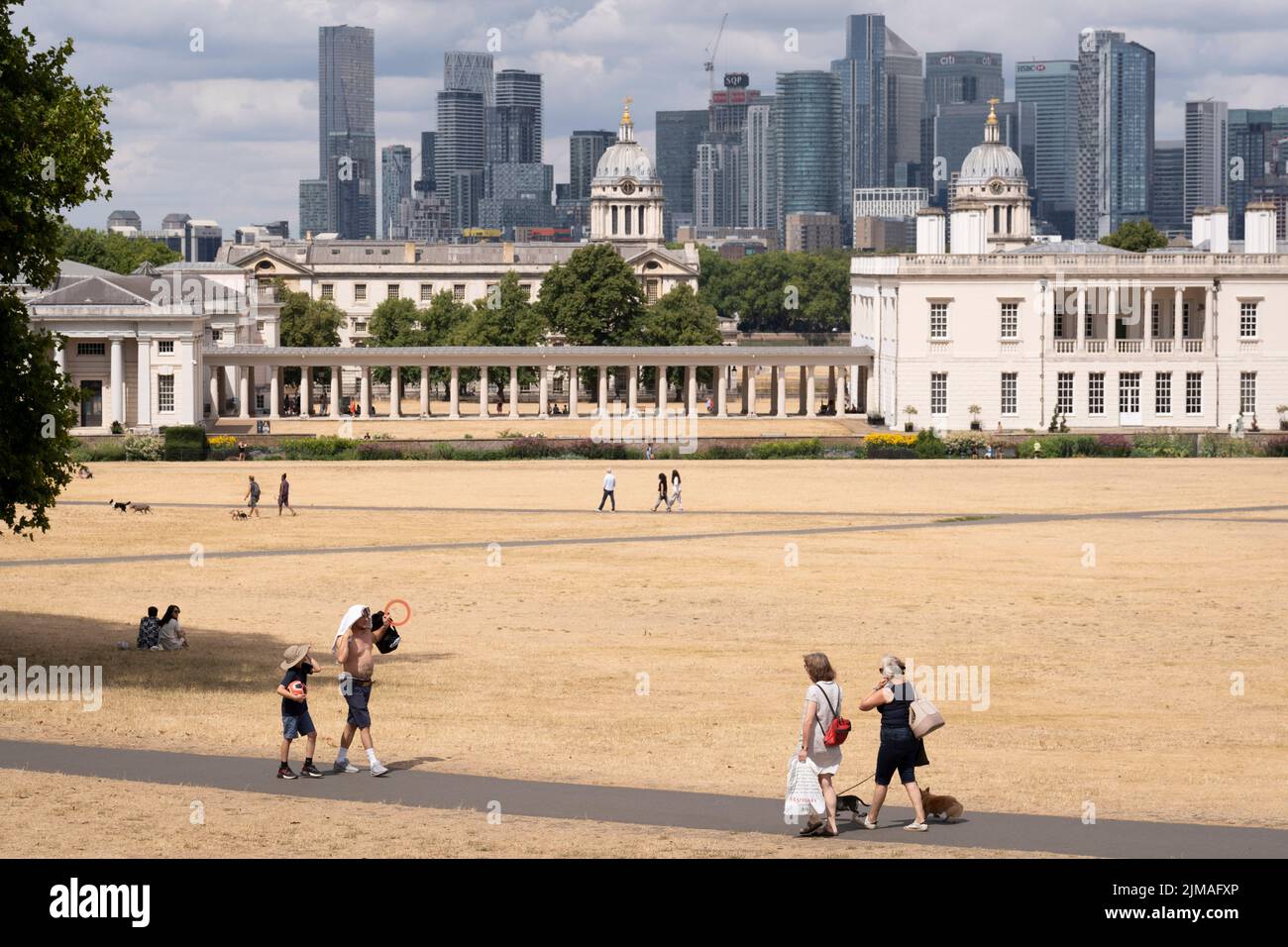 Overlooked by the former royal residence, Queen's House, park users walk through a parched grass landscape in Greenwich Park as the UK's heatwave and drought continues into August with little rain having fallen in London and south-east England, on 4th August 2022, in London, England. Queen's House is a former royal residence built between 1616 and 1635 near Greenwich Palace. Stock Photo