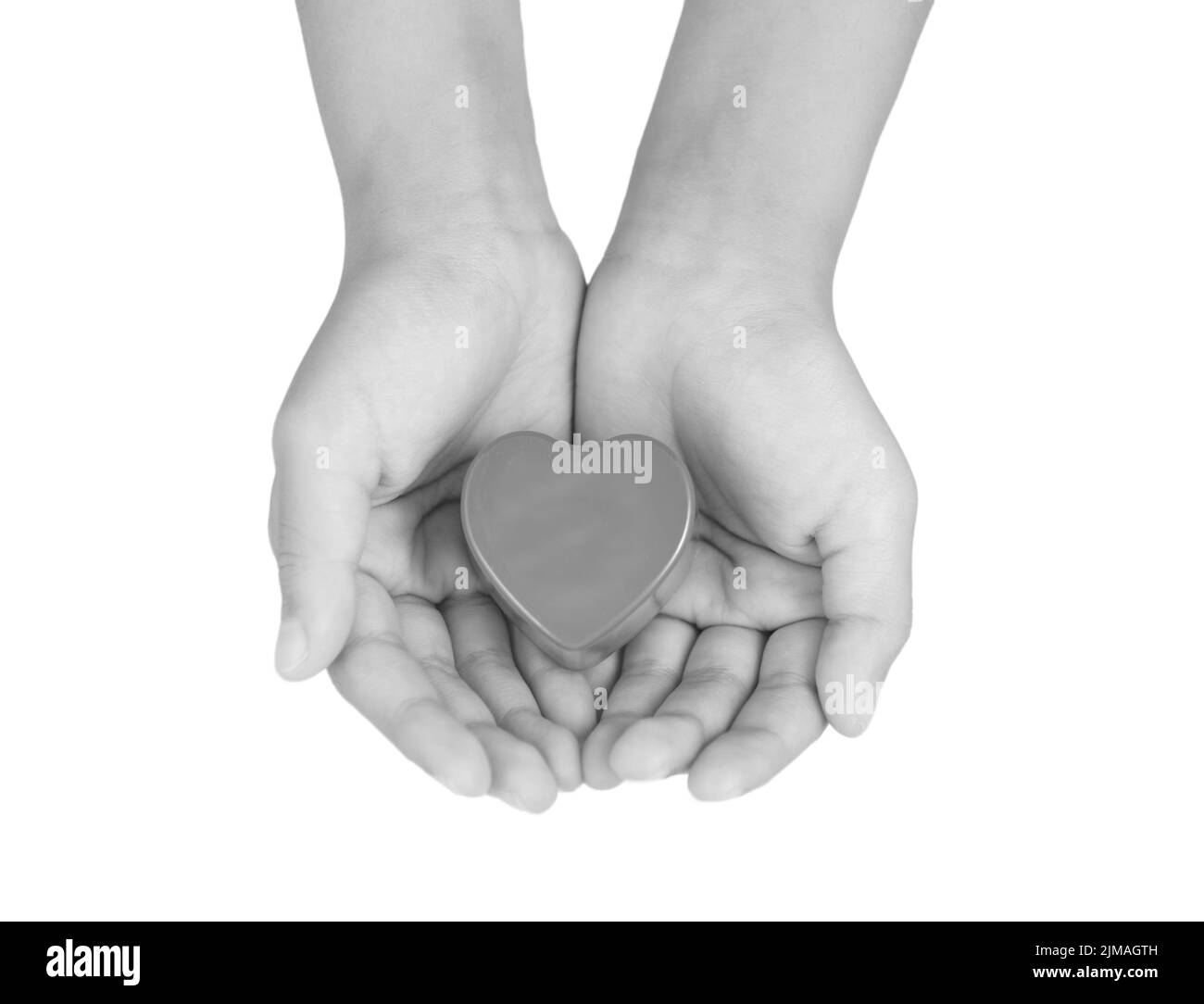 Heart care, medical concept. Heart in the hands of a child. Black and white image Stock Photo