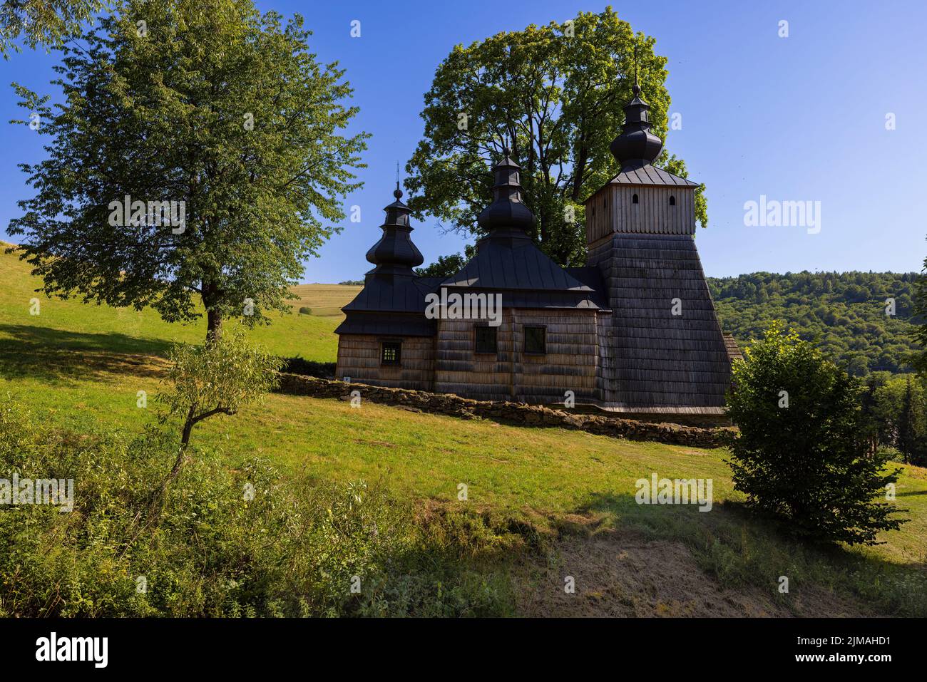 Old orthodox church under the tree on the hill at clear day. No people, no clouds. Stock Photo
