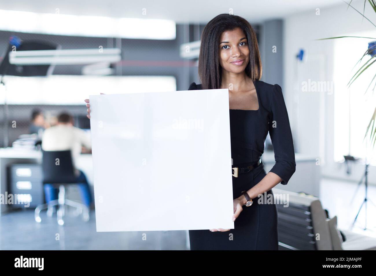 Pretty, young business lady in black strong suite hold empty paper Stock Photo