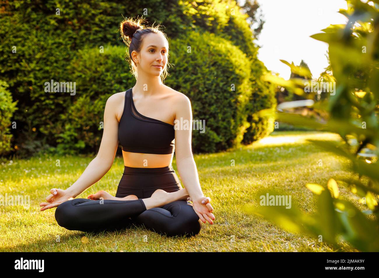 Young peaceful woman sitting in lotus pose, breathing and meditating ...