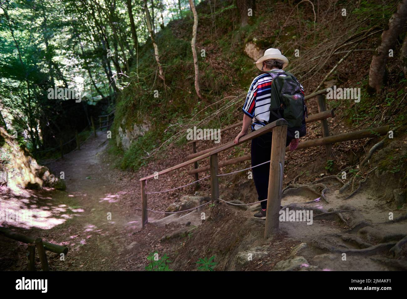 Middle-aged woman with hat and backpack walking, Baquedano, Navarra, Spain, Europe Stock Photo