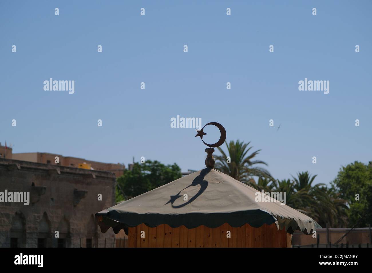 Turkish flag symbol, crescent moon and star, its shadow on roof during sunrise. Stock Photo