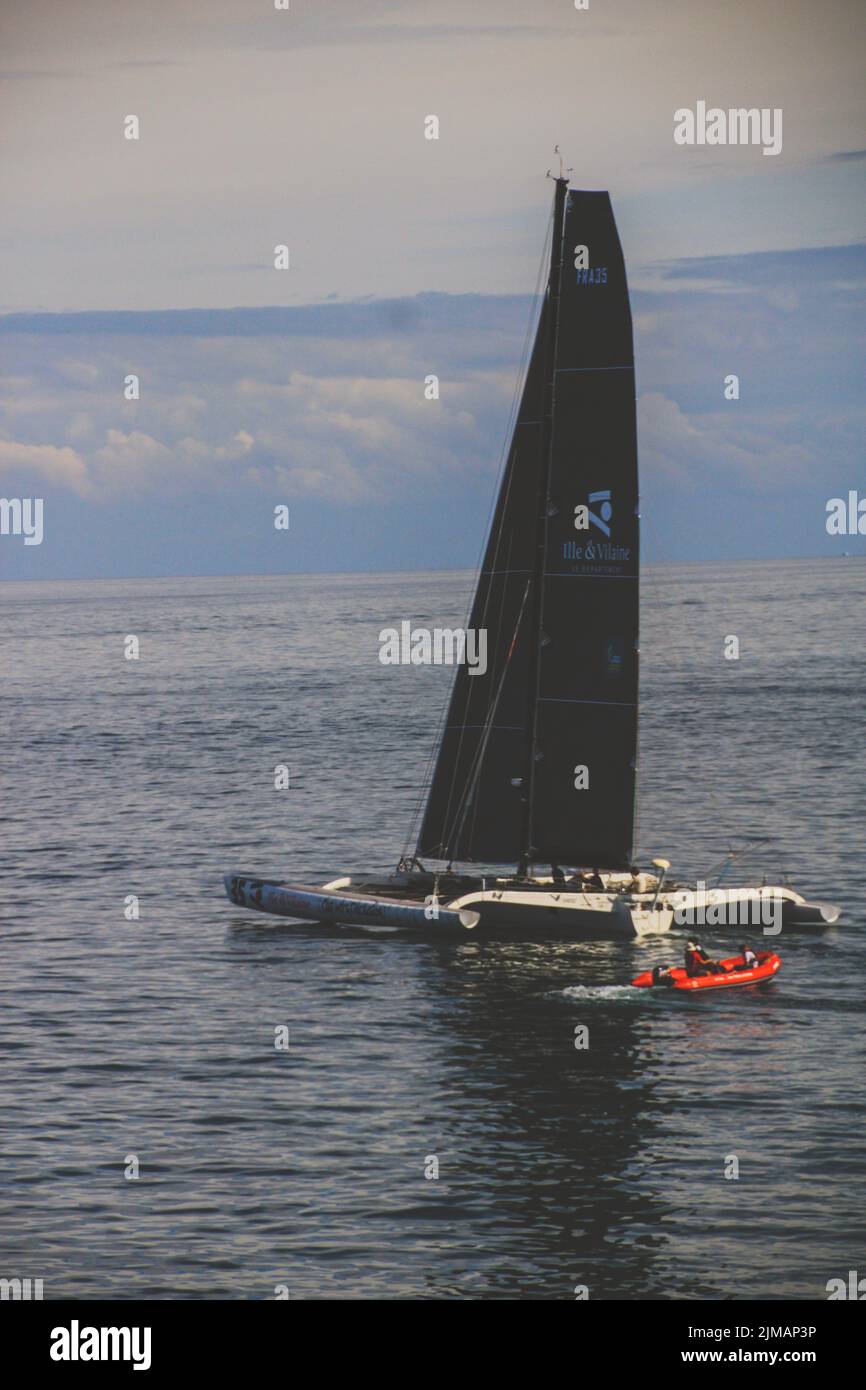 A vertical shot of a black yacht sailing in the middle of the ocean