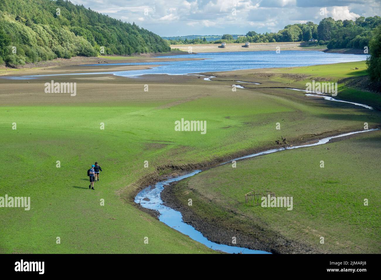 North Yorkshire, UK. 5th August, 2022. Walkers trek across the empty and dry basin of Lindley Wood Reservoir. Lindley Wood Reservoir, used by Yorkshire Water to supply drinking water to Leeds and surrounding areas, is nearly empty and dry.  Credit: Bradley Taylor / Alamy News Stock Photo