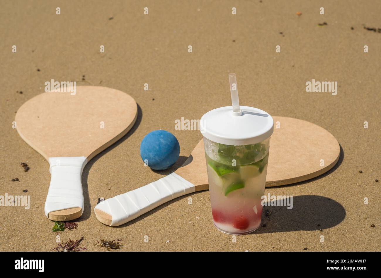 Beach tennis rackets in sand, caipirinha drink Stock Photo