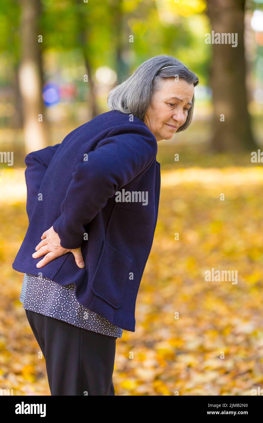 Senior woman suffering from backache outdoors Stock Photo
