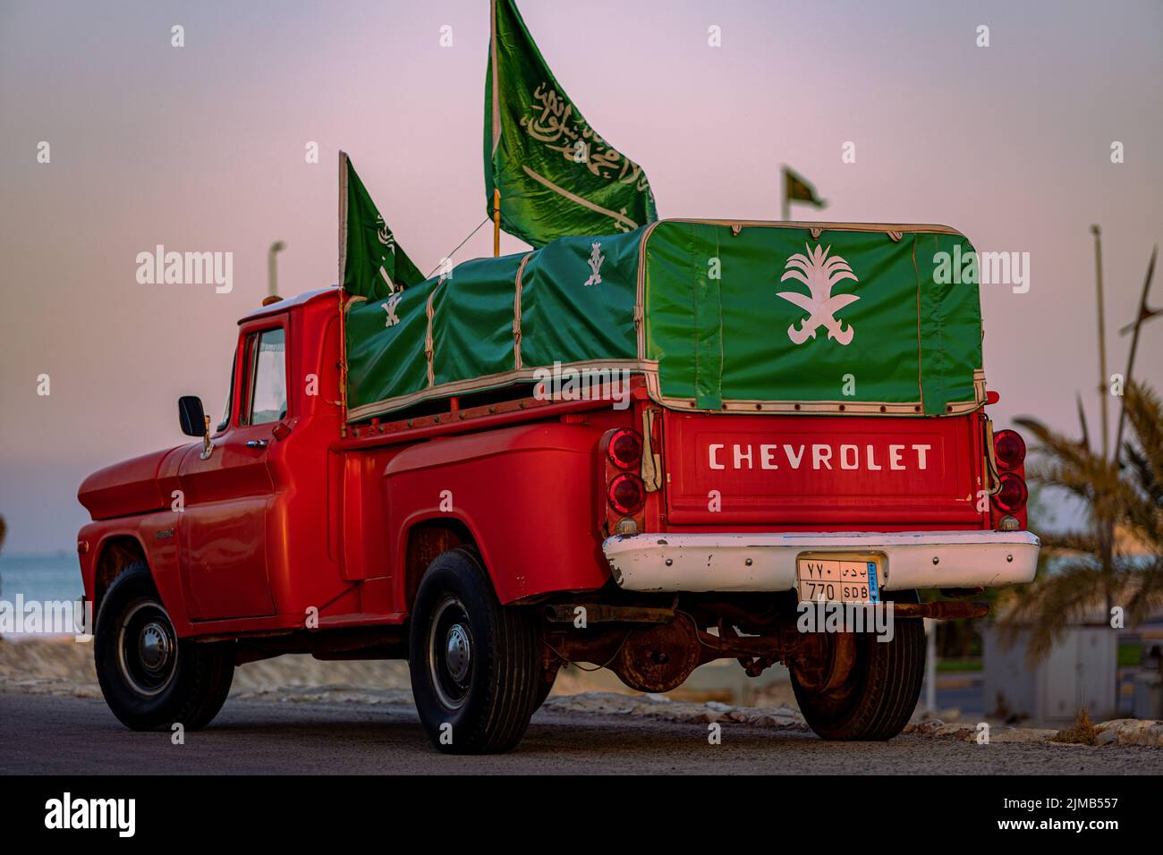A red Chevrolet pickup car with National Day flags in Saudi Arabia Stock Photo