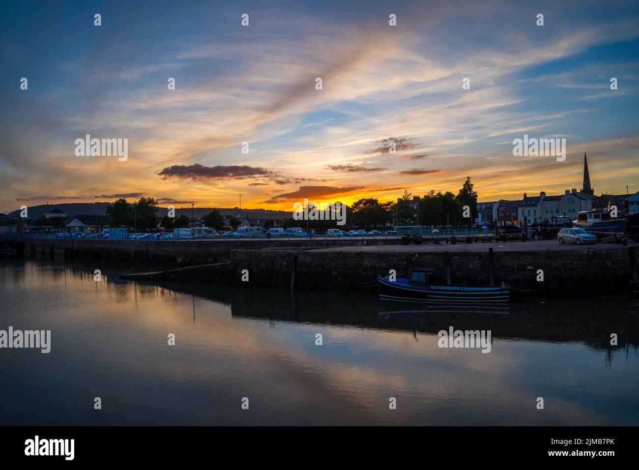 A beautiful sunset in Carrickfergus harbor with waterscape and boats Stock Photo