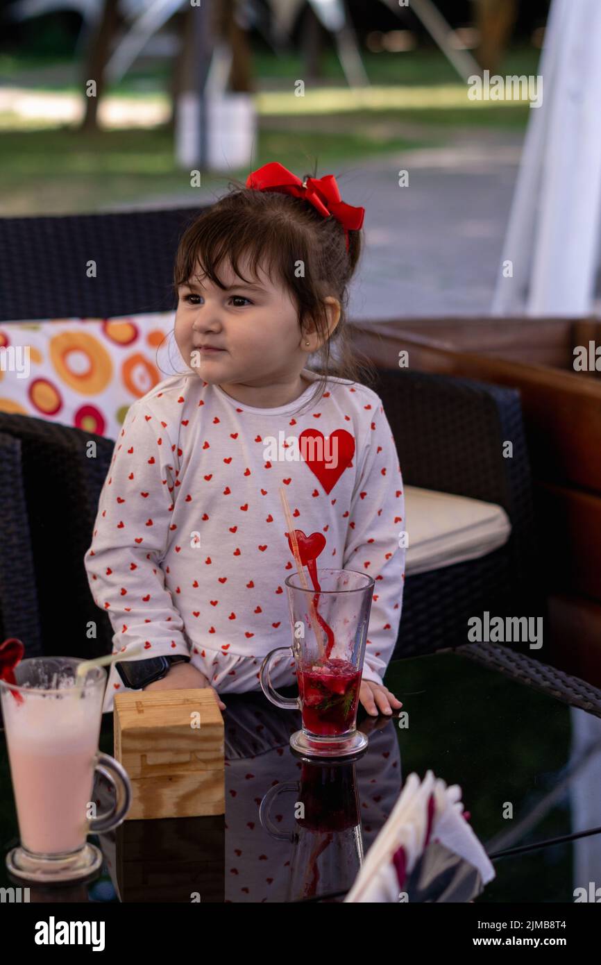 A vertical shot of a little girl in a cafe looking to the right. Stock Photo
