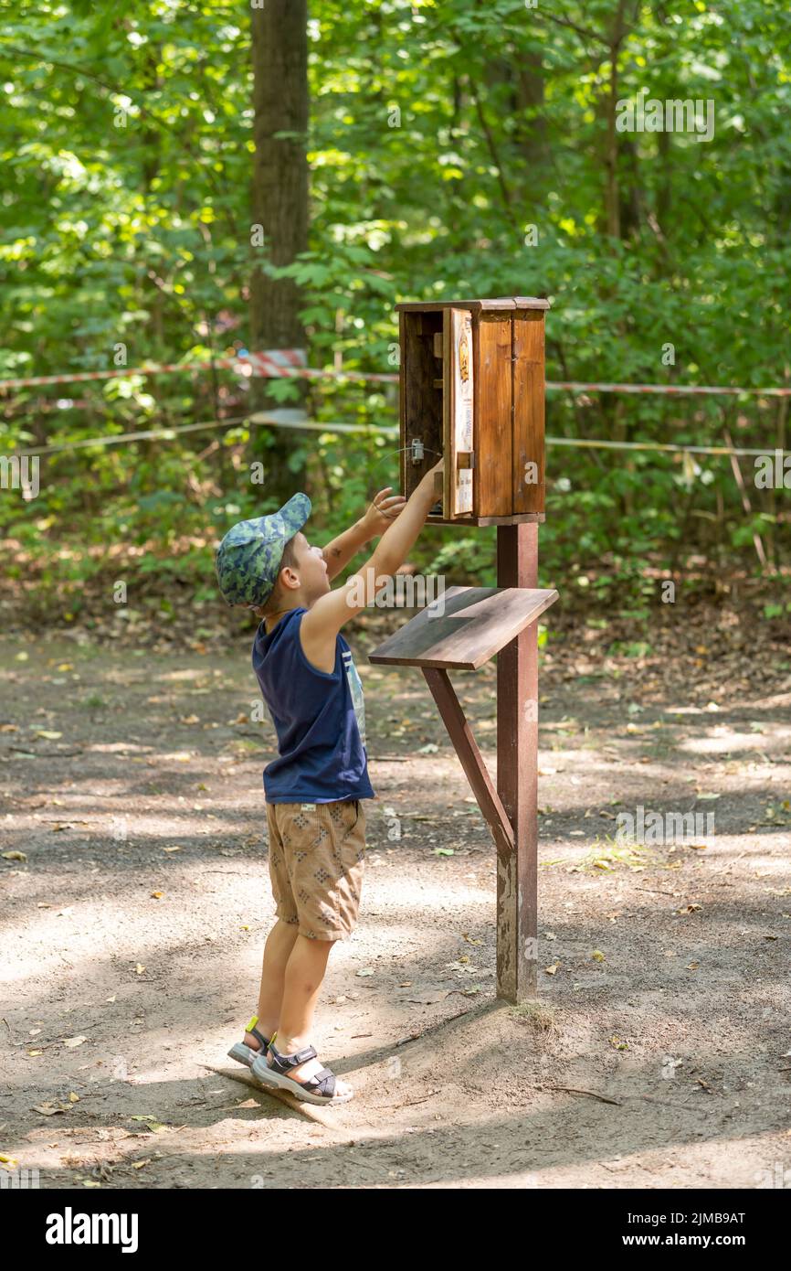 A young boy taking a stamp as a part of a excursion game in the new zoo on a warm summer day. Stock Photo