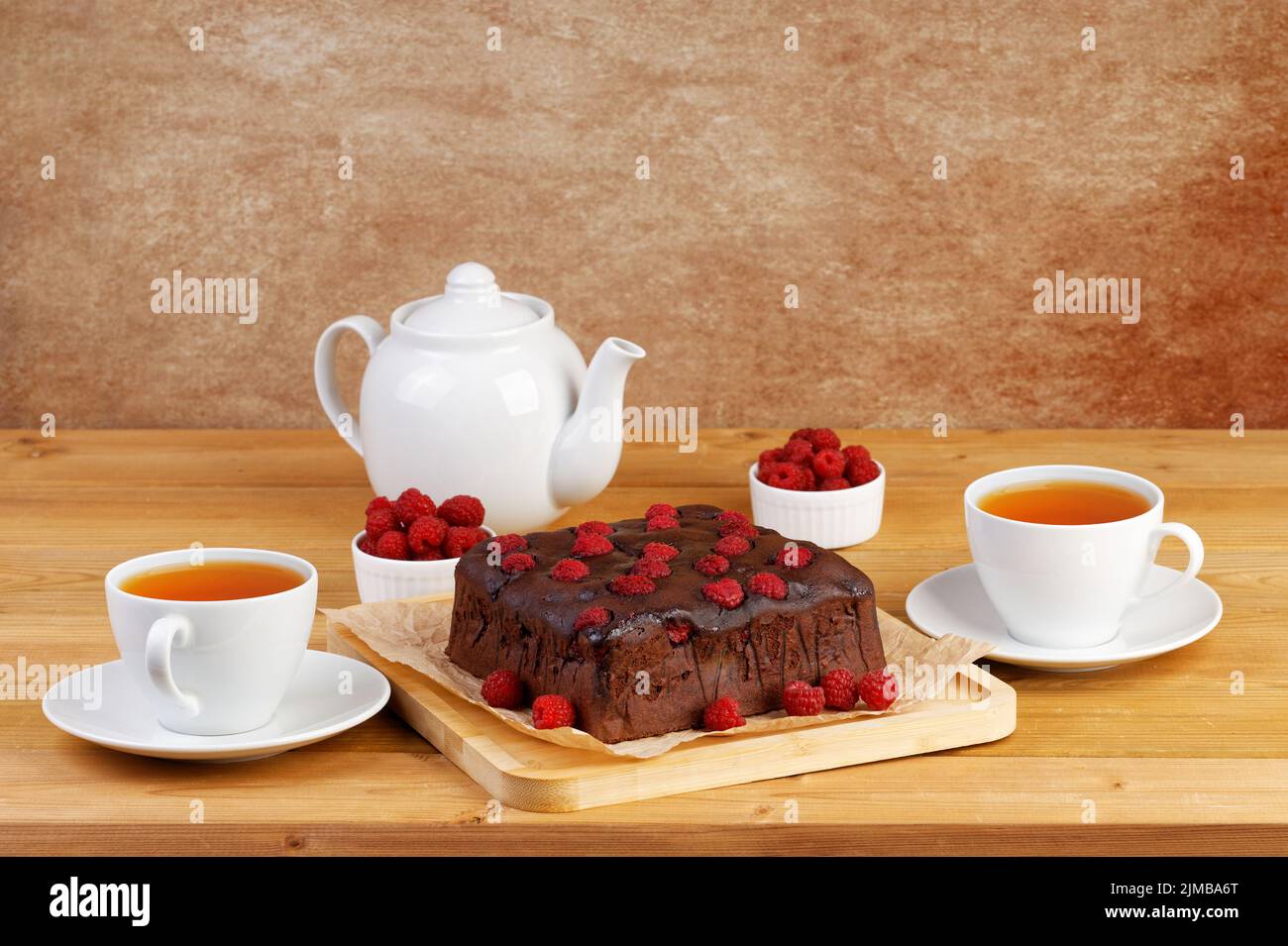 Homemade cake with raspberries and two cups of tea on wooden table. Copyspace. Stock Photo
