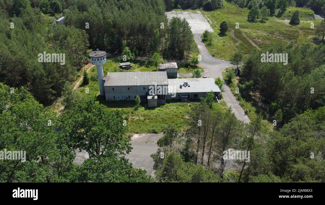 An aerial view of an old abandoned building in a forest surrounded by ...