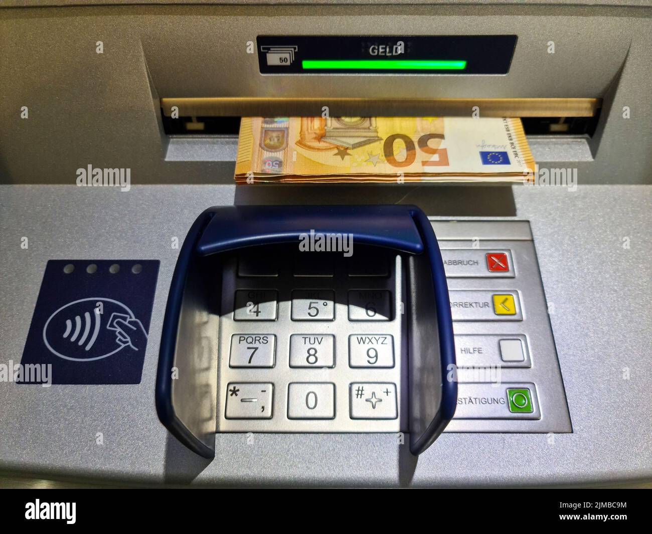 A closeup shot of a keypad on an ATM in a bank branch with euro notes in circulation Stock Photo