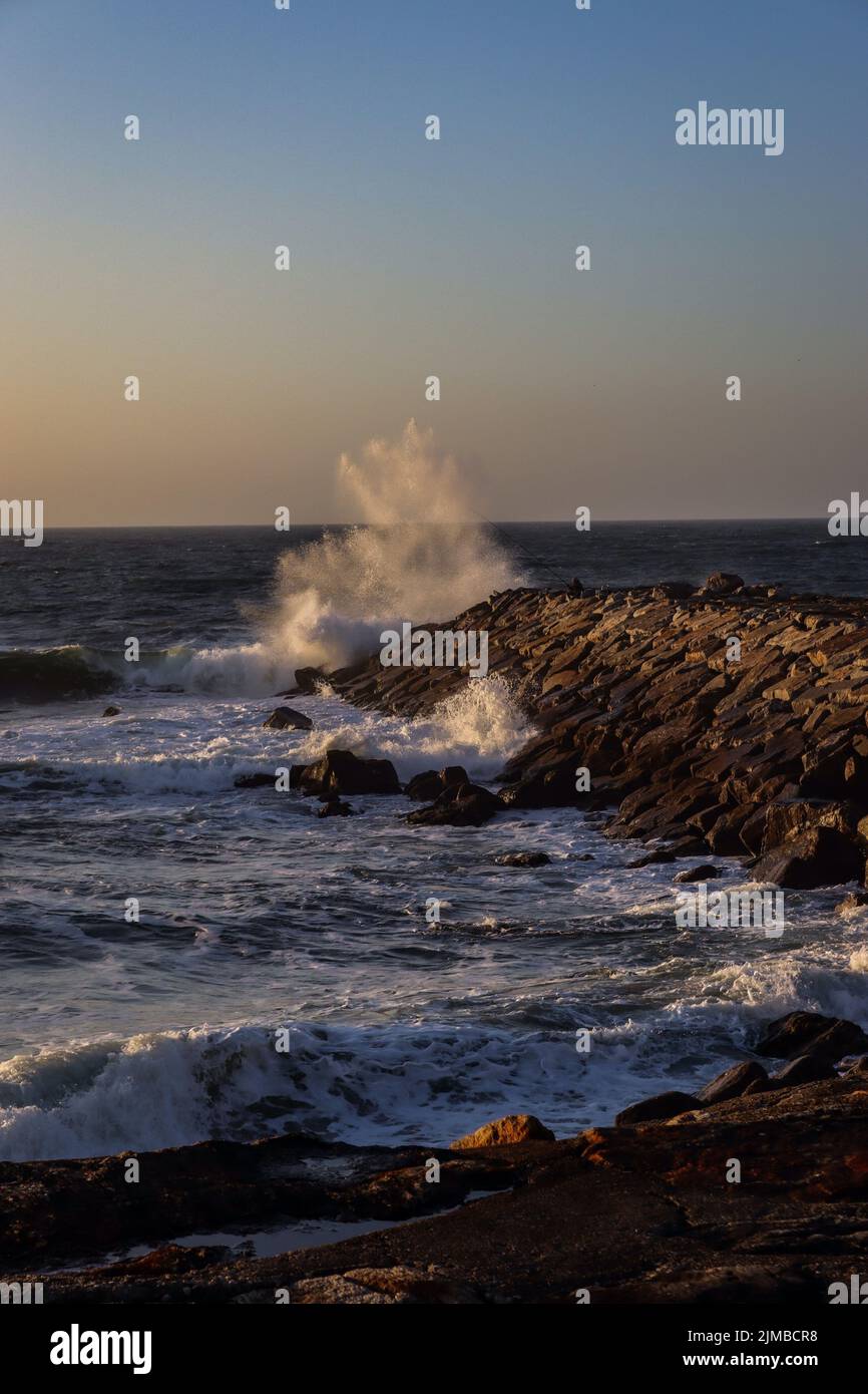 A vertical view of waves hitting rocks during sunset Stock Photo - Alamy
