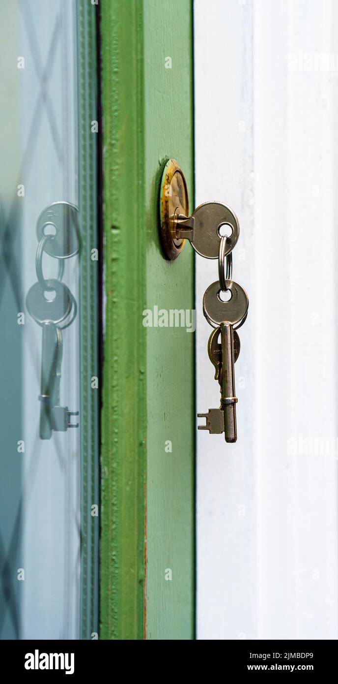 house keys in yale lock in wooden door of house Stock Photo