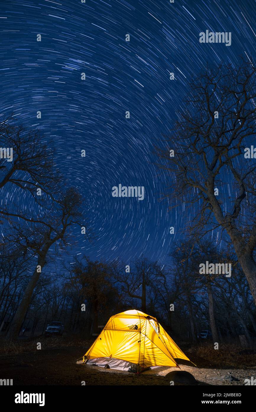 A vertical shot of an illuminated tent with star trails in Dori Campground Stock Photo