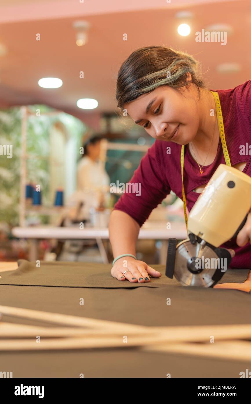 Suing Cloth Vertical photo of a woman using an electric cloth cutter in an sewing ...
