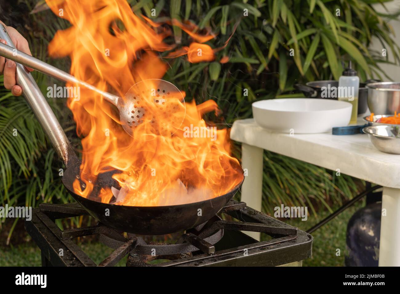 Person cooking with a pan and a portable stove in a garden Stock Photo