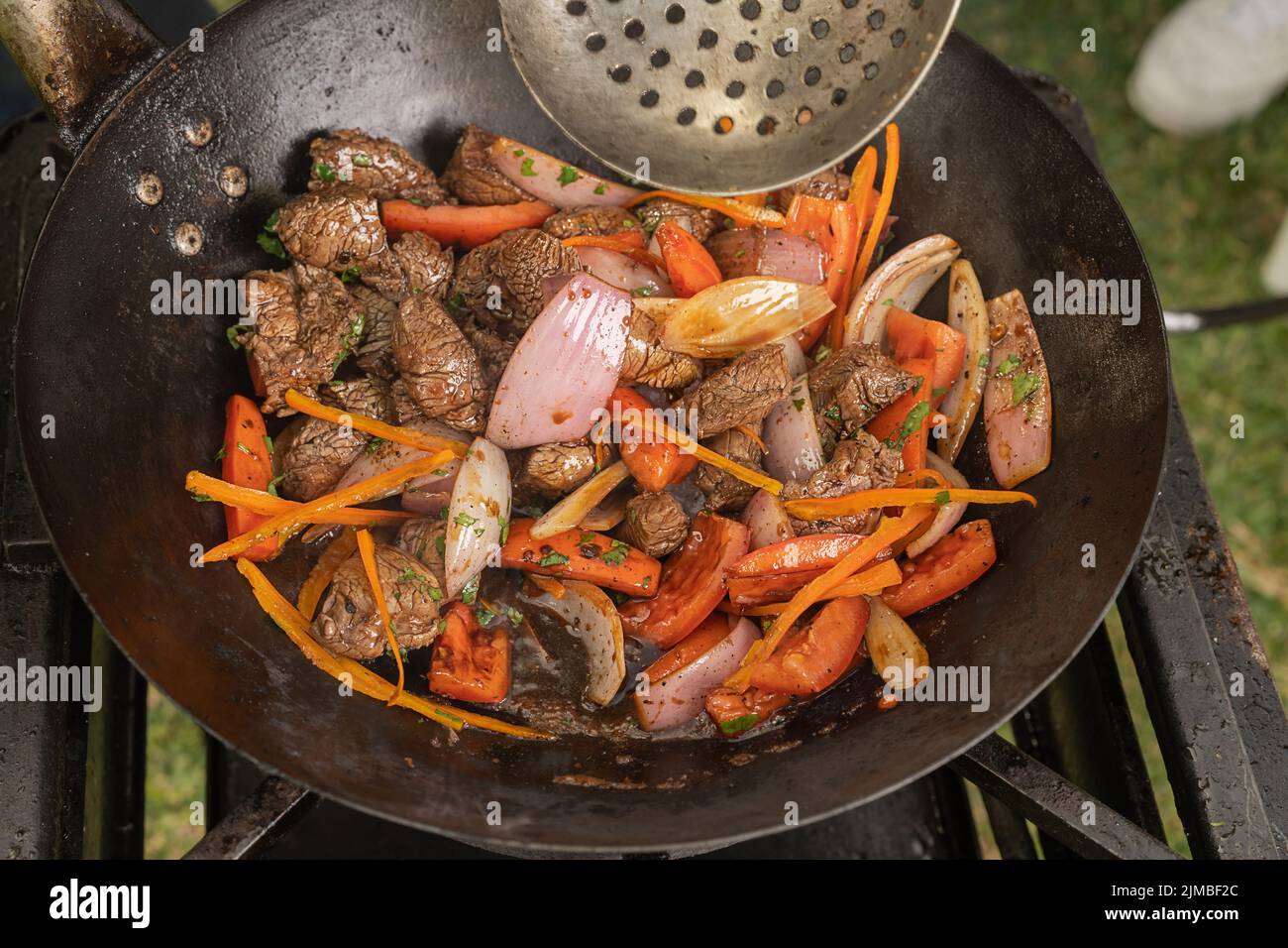 Top view of a pan with meat and veggies on a portable stove in a garden Stock Photo