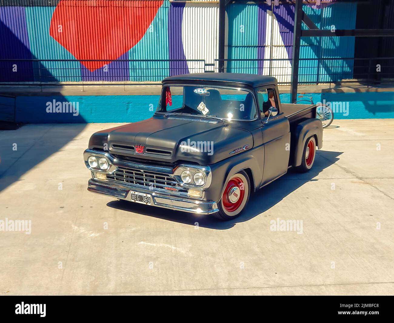 old black Ford F100 pickup truck Custom Cab Flareside bed Twin Beam circa 1960 parked in a warehouse yard. Classic car show. High angle. Copyspace Stock Photo