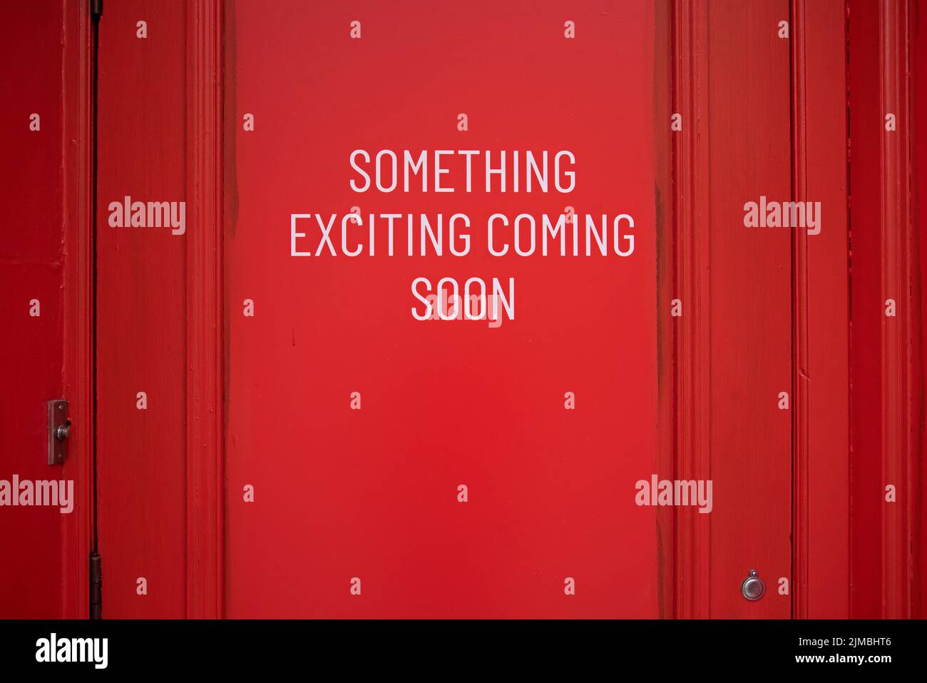 Red doorway with the words, 'Something Exciting Coming Soon'. Stock Photo