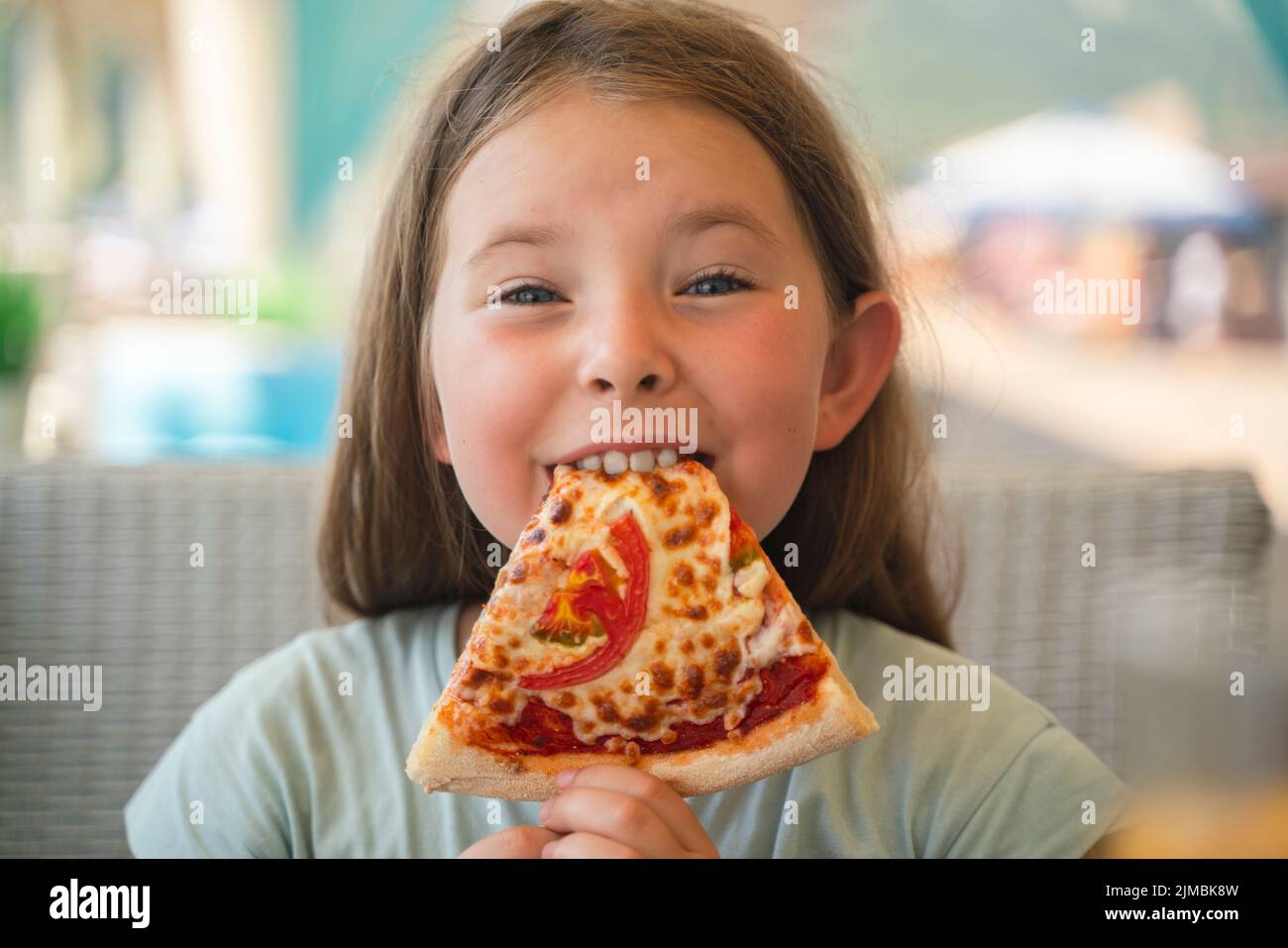 A young girl with plaits is eating a piece of pizza. High quality photo Stock Photo