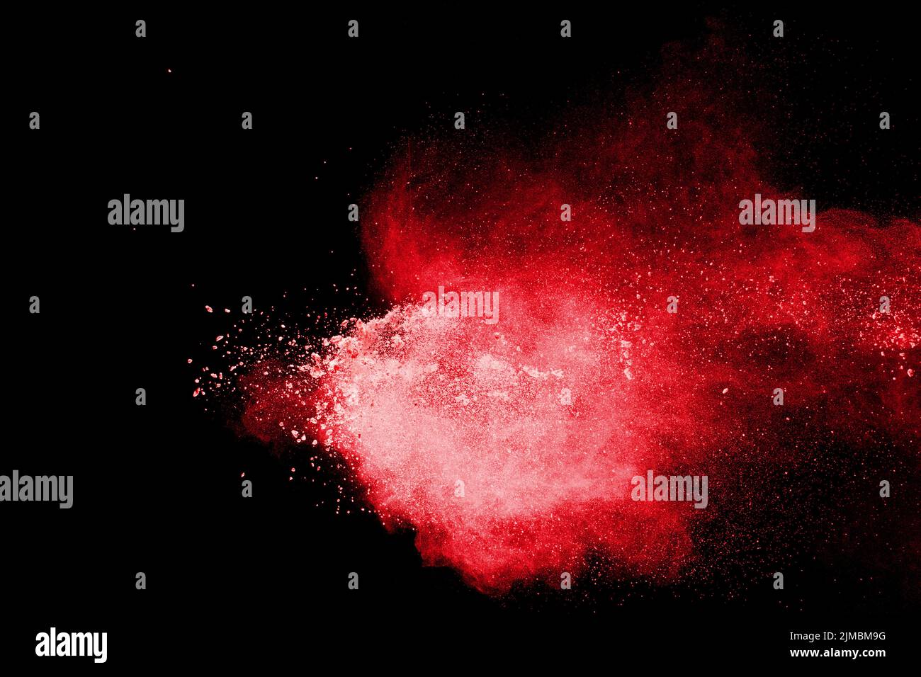 Red color powder explosion on black background.Freeze motion of red dust particles splashing. Stock Photo