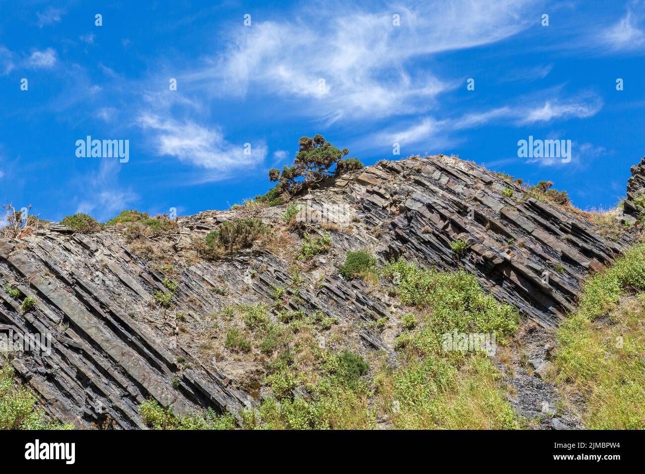 Mountainous landscape featuring jagged rocks and flora set against a blue sky. Health, fitness, walking, hiking or active leisure time concept. Stock Photo
